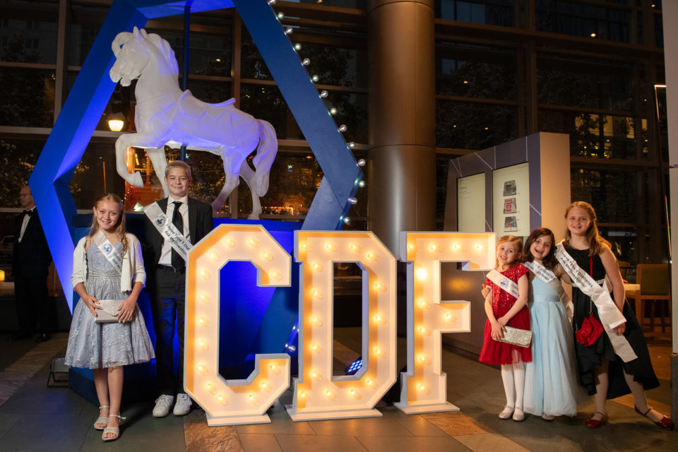A group of children standing around the letters C,D and F.