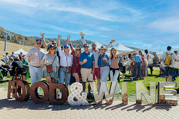 A group of people standing together outside, each holding a glass of wine