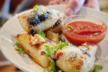 A plate with garlic knots and a bowl of red sauce