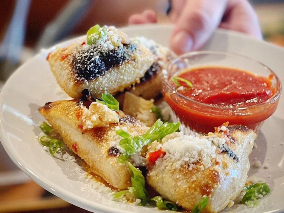 A plate with garlic knots and a bowl of red sauce