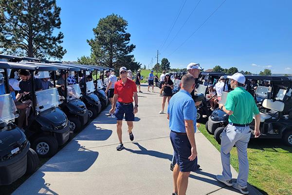People standing around on a sidewalk in front of golf charts