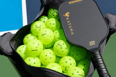 A bag of pickleballs and a paddle