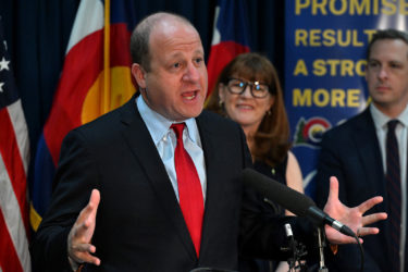 Governor Jared Polis speaks at a podium