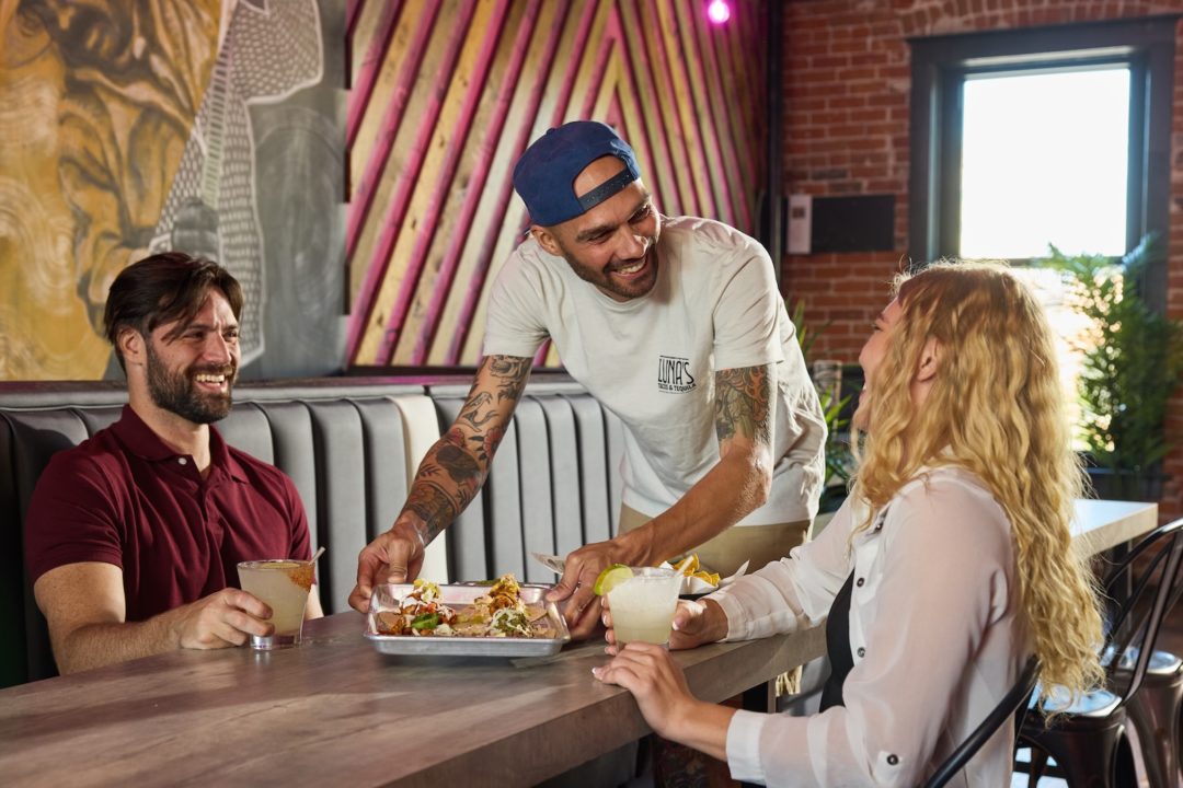 A server places food down in front of customers at Luna's Tacos & Tequila