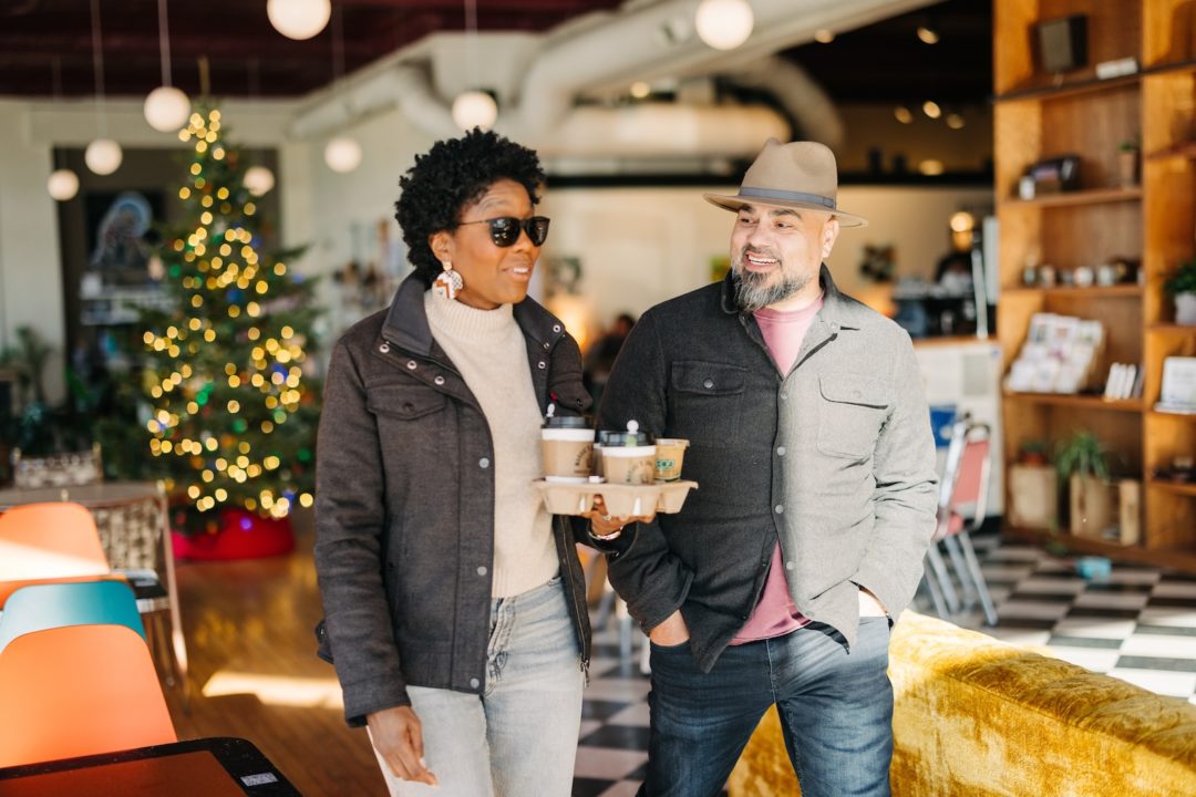 Two people holding cups of coffee inside Margie's Java Joint