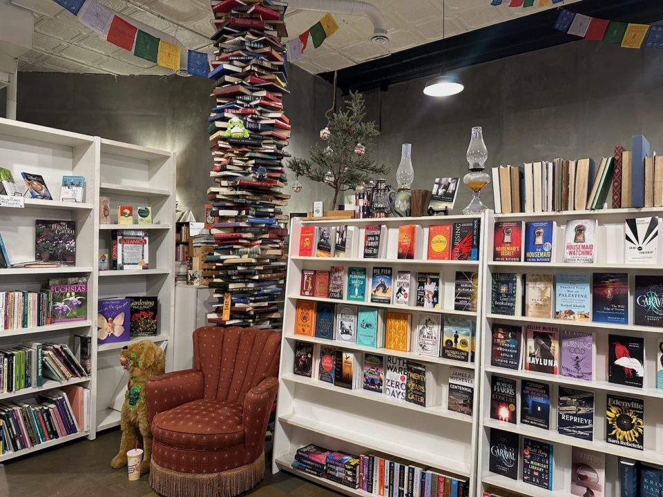 A chair, shelves of books, and a decorative tower made out of books at the Midnight Oil.