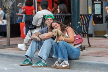 Two humans pose with a dog