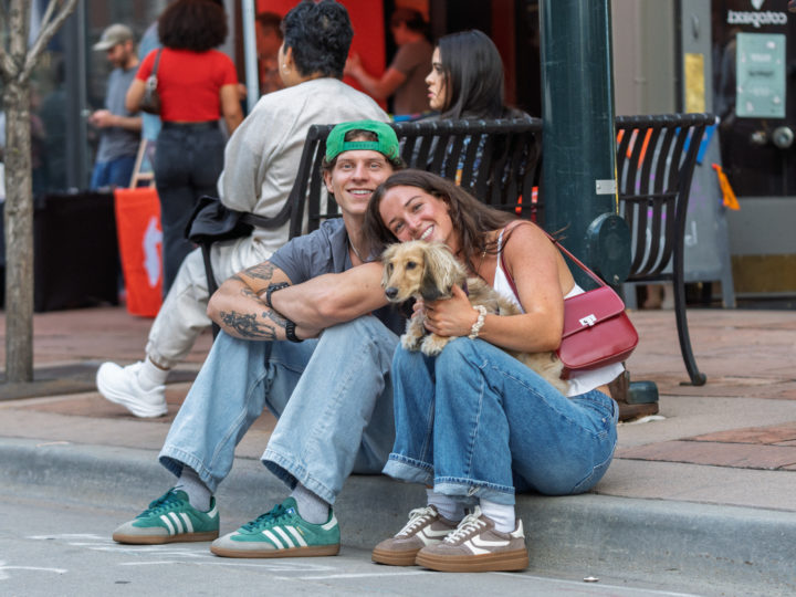 Two humans pose with a dog