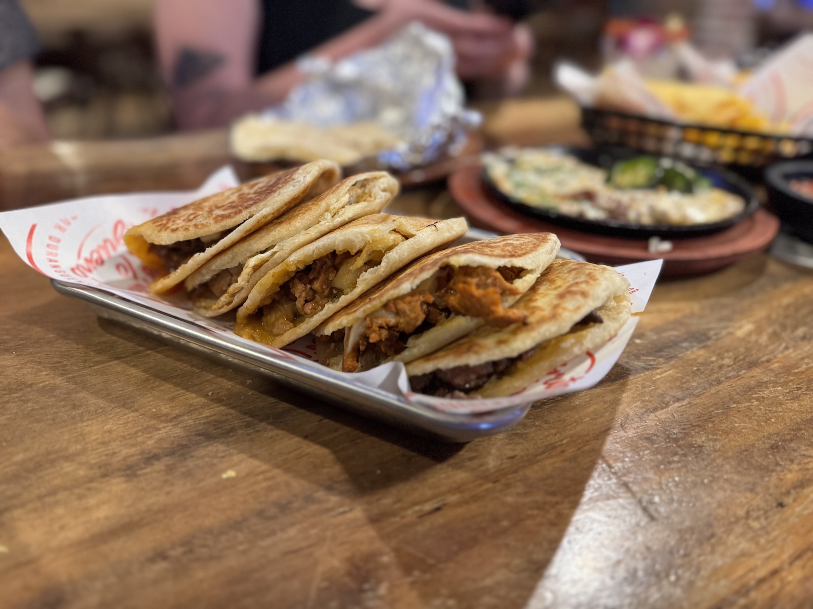 Five gorditas stuffed with meat on a rectangular tray