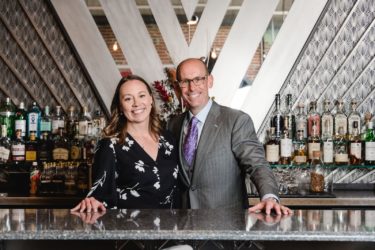 Nicole and Scott Mattson dressed up behind the Art Deco bar of their restaurant.
