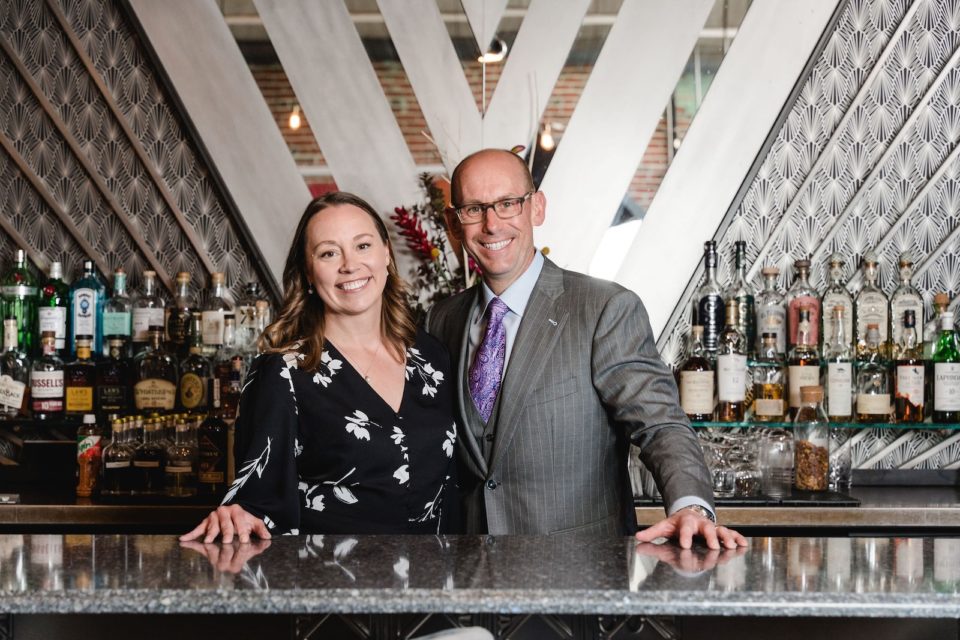 Nicole and Scott Mattson dressed up behind the Art Deco bar of their restaurant.