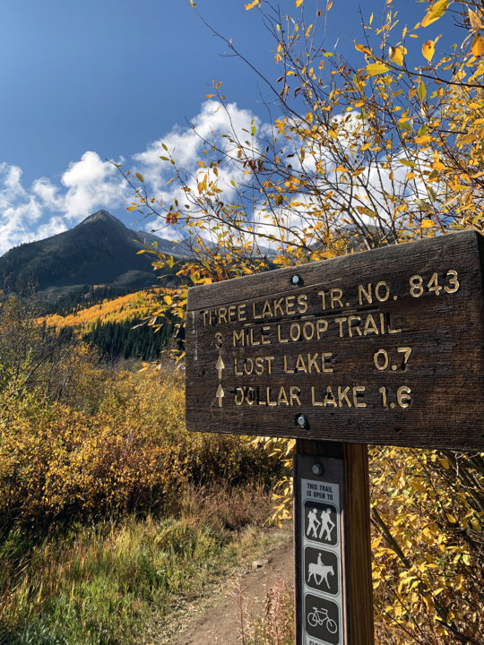 A sign for the Three Lakes Loop in front of golden aspens