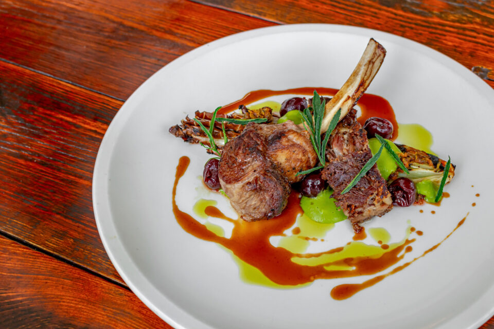 Lamb with sauce and garnishes on a white plate