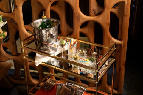 A bar cart with ingredients, a silver ice bucket and glassware for making martinis
