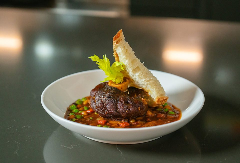 Venison osso bucco with a slice of bread in a white bowl