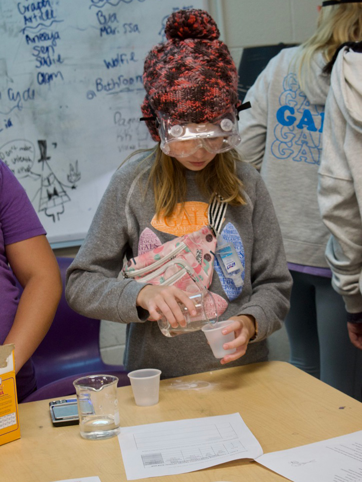 Middle school girl pour liquid into a beaker
