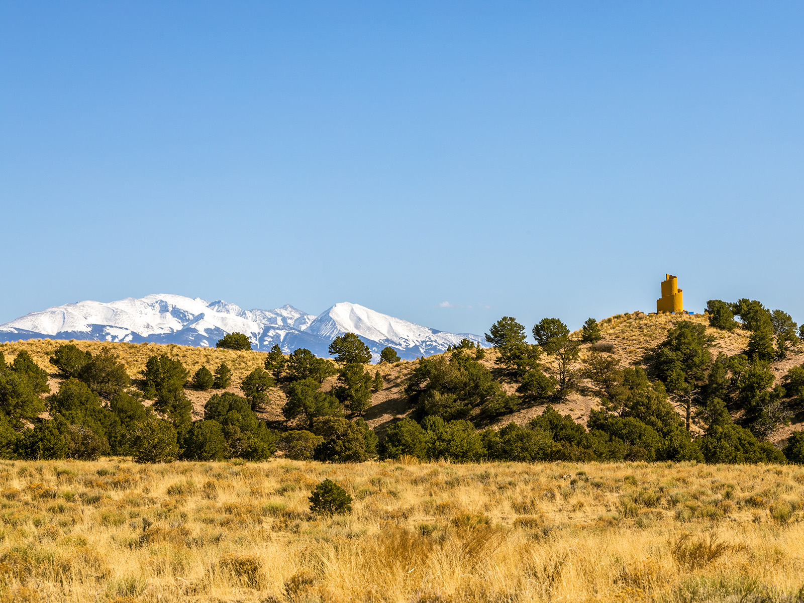 yellow ziggurat in front of snowy mountains