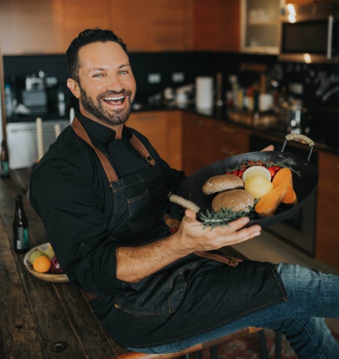Yaniv Cohen, also known as the Spice Detective, smiles for a photo holding a pan of food