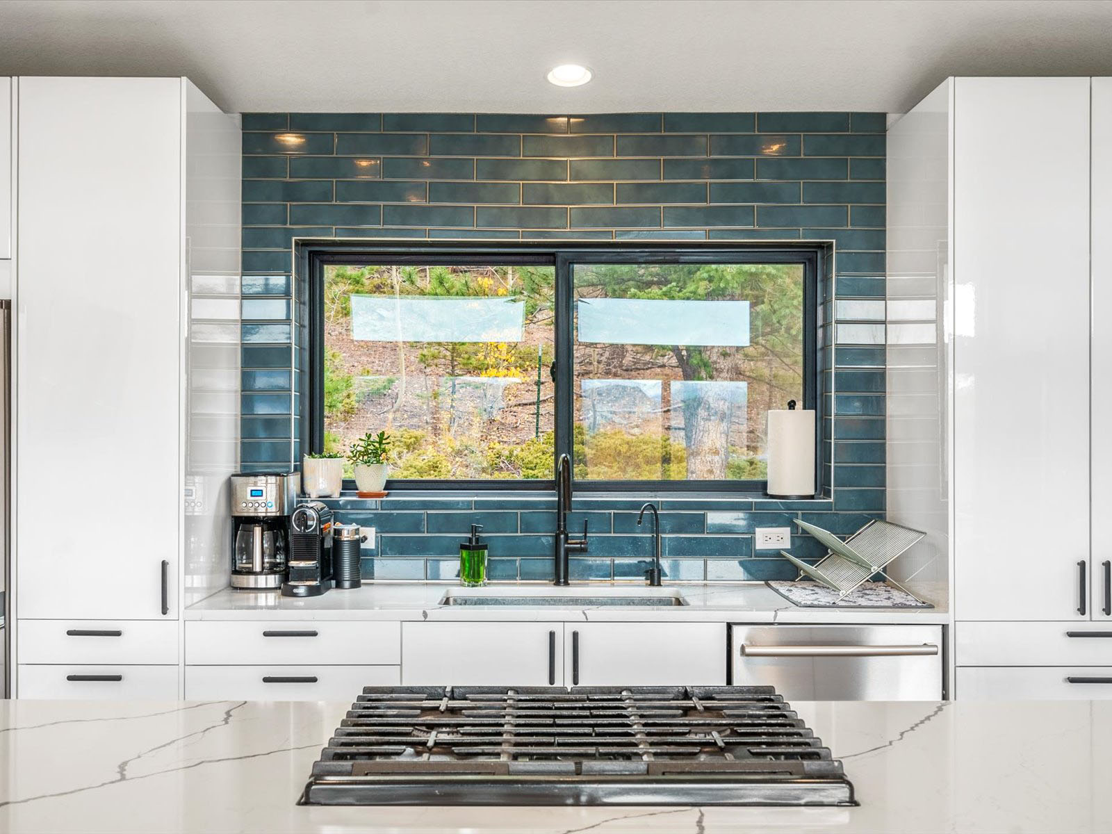 Kitchen with a gas stove on an island and a blue backsplash framing a window