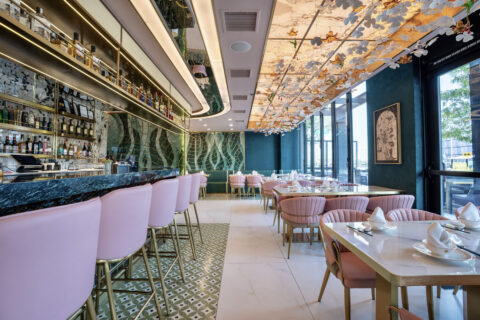 Dining room with pink scaloped chairs, emerald tile on the walls, and flowers on the ceiling