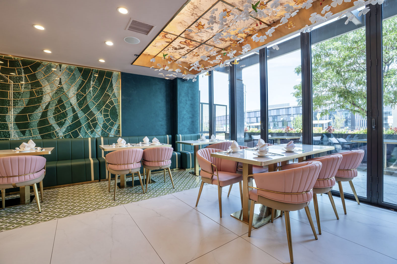 Dining room with pink scalloped chairs, emerald green tiled walls, and flowers on the ceiling