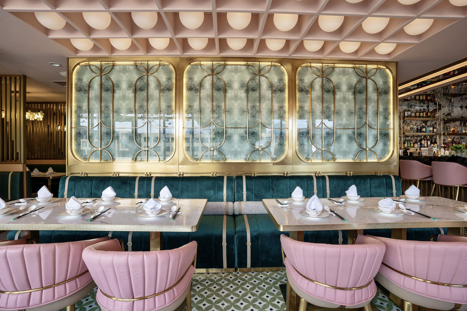 Dining room with pink scalloped chairs, orb lighting, and green tile walls