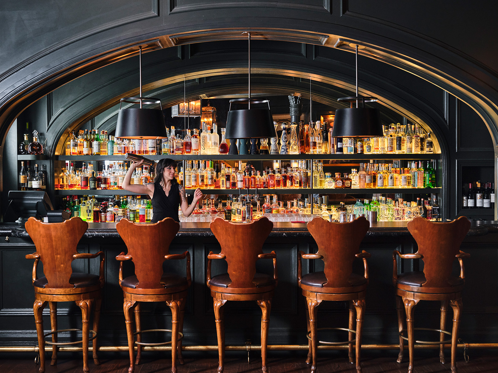 Bartender shakes a drink behind a bar