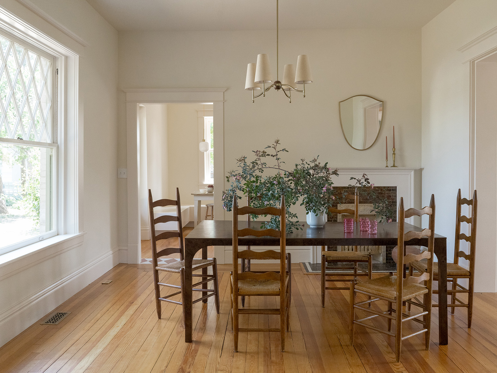 White dining room with a wooden table and chairs and chandelier