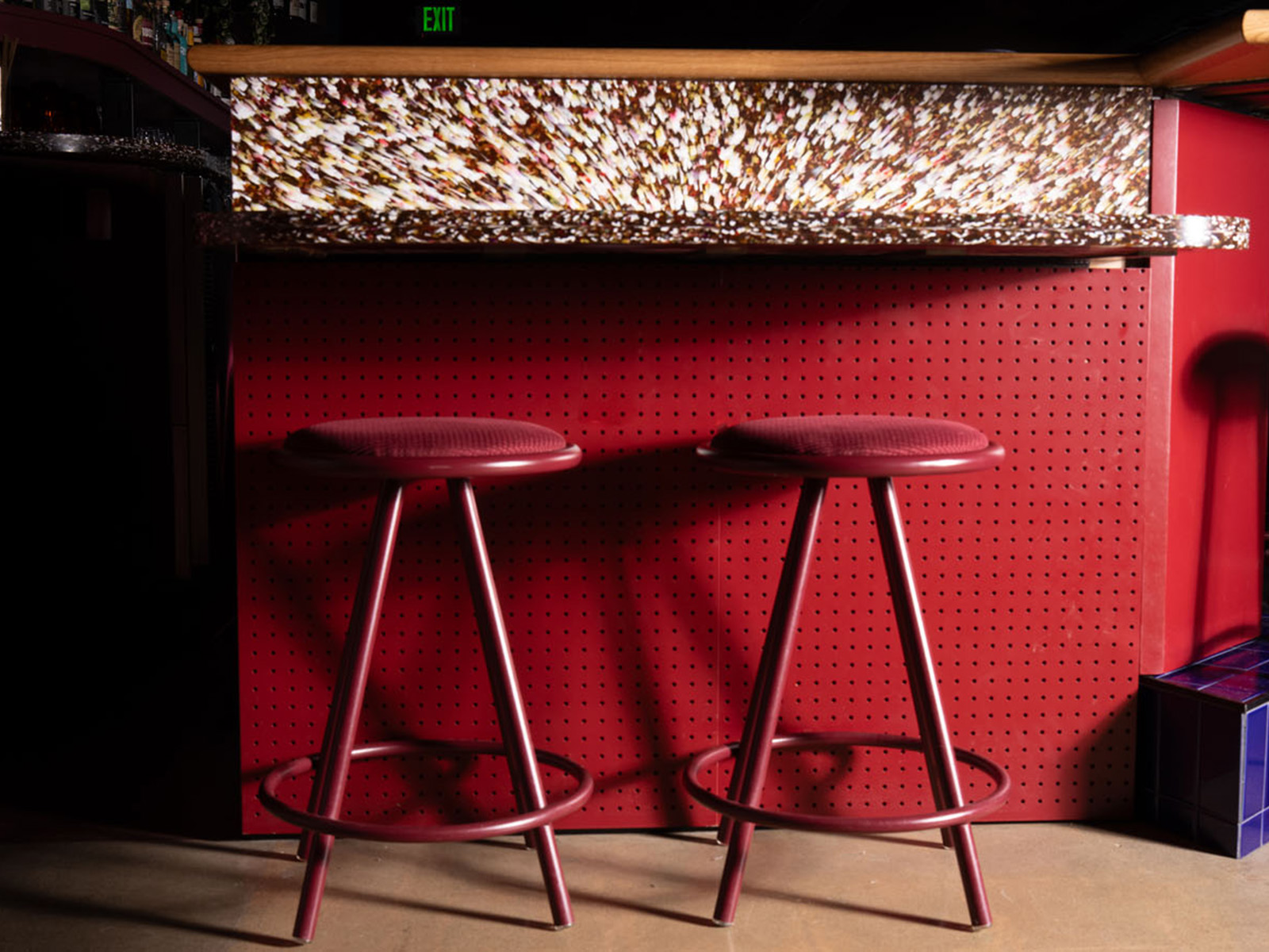Red barstools against a red pegboard bar