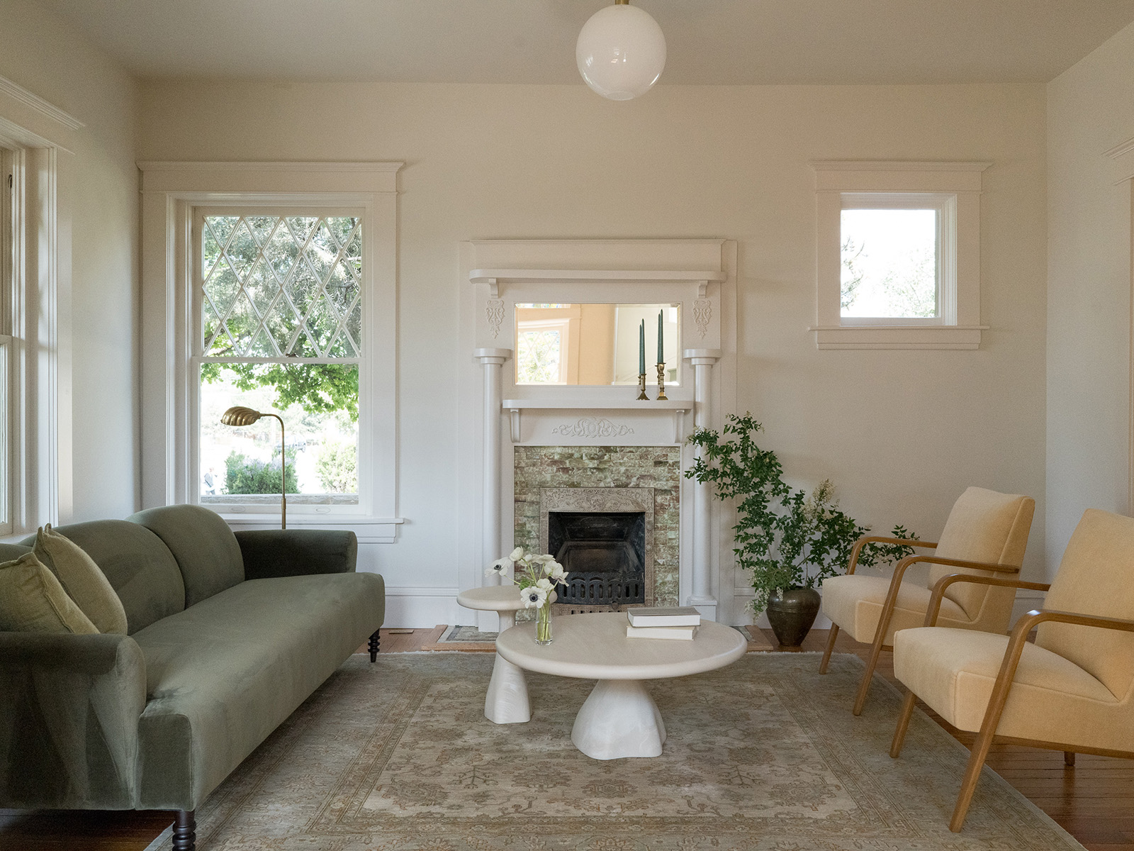 Living room with a sage green couch, fireplace, and thonet chairs