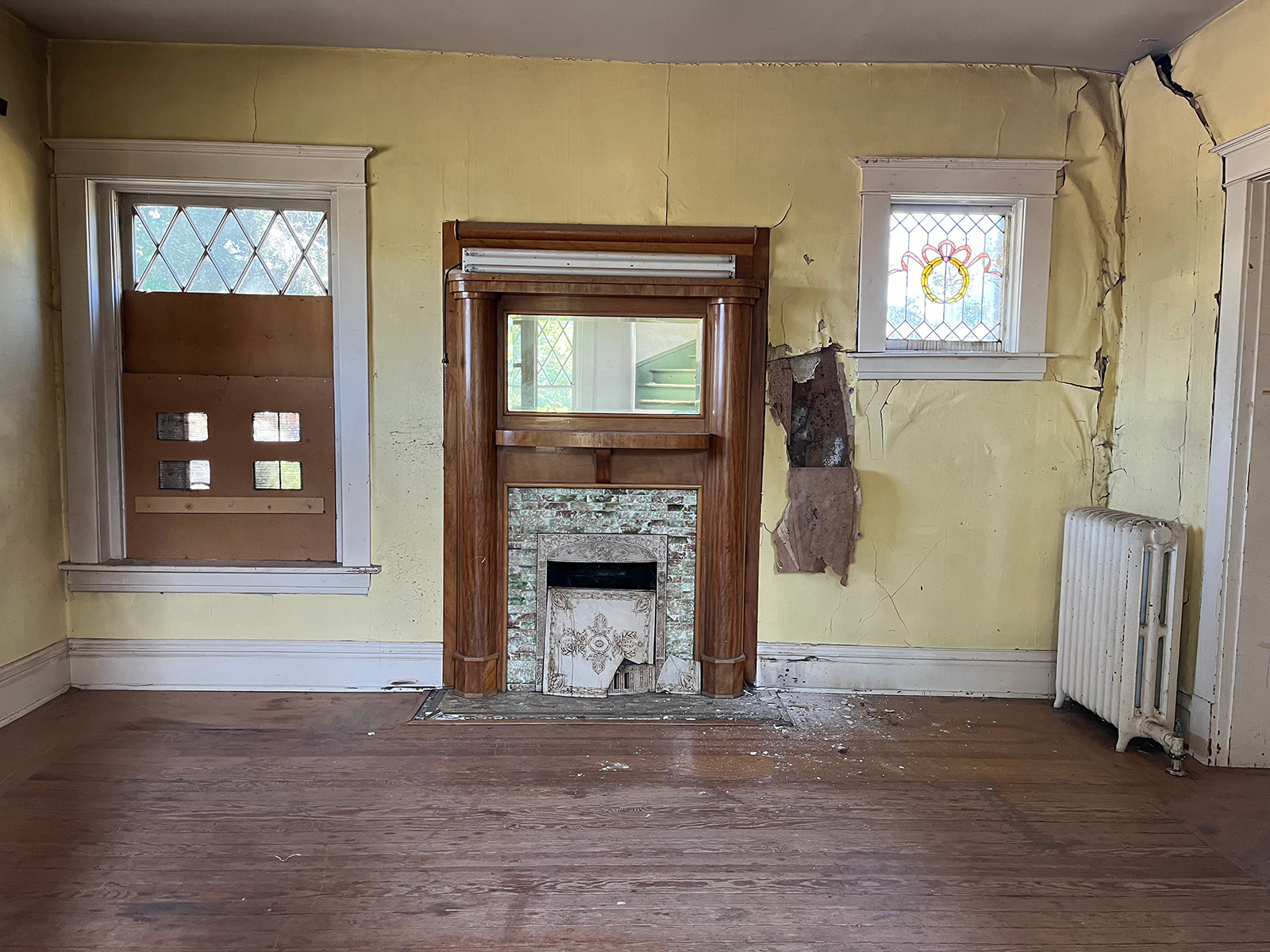 A derelict living room with peeling wallpaper