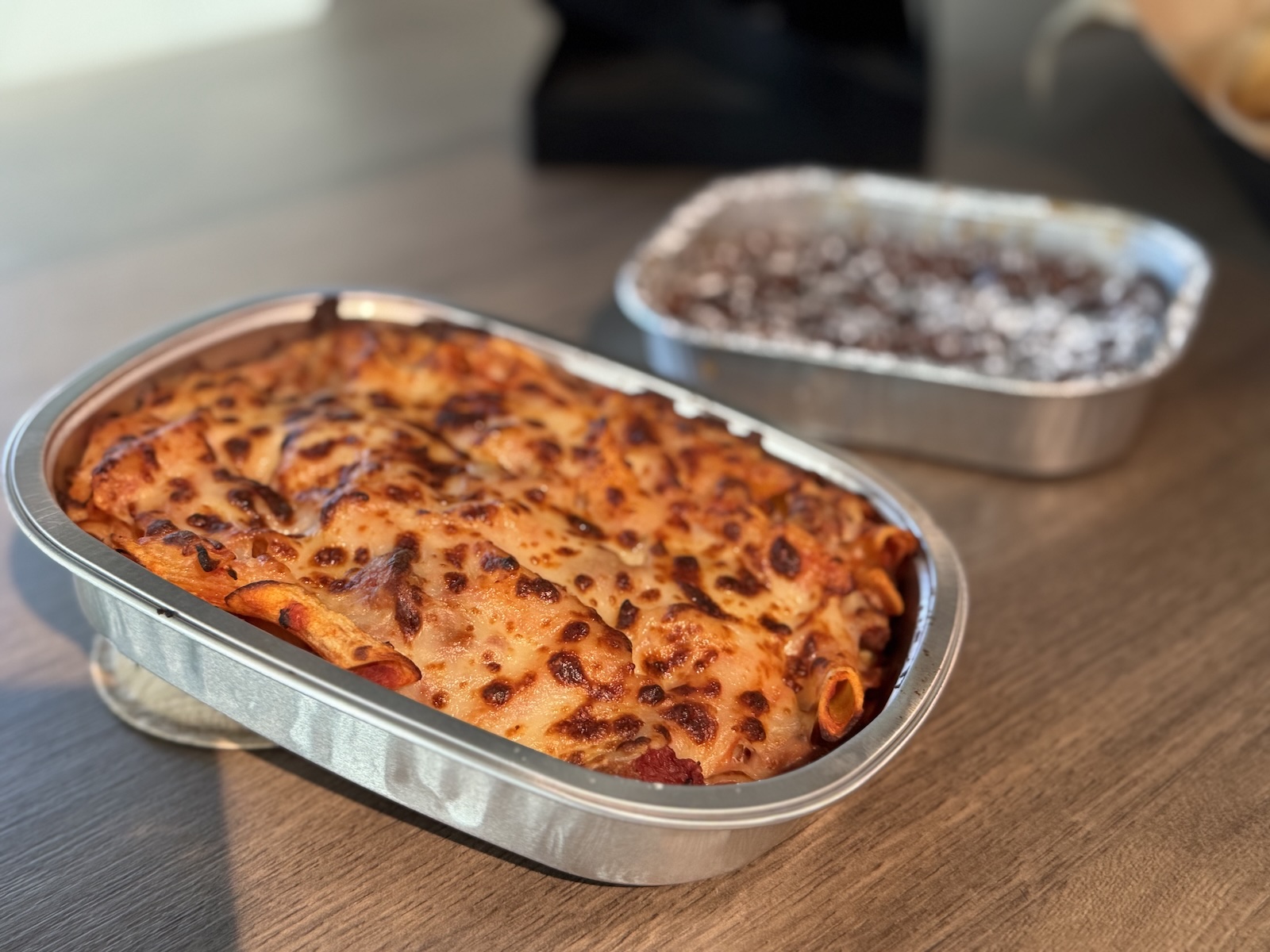 A metal pan of baked pasta with browned cheese on top