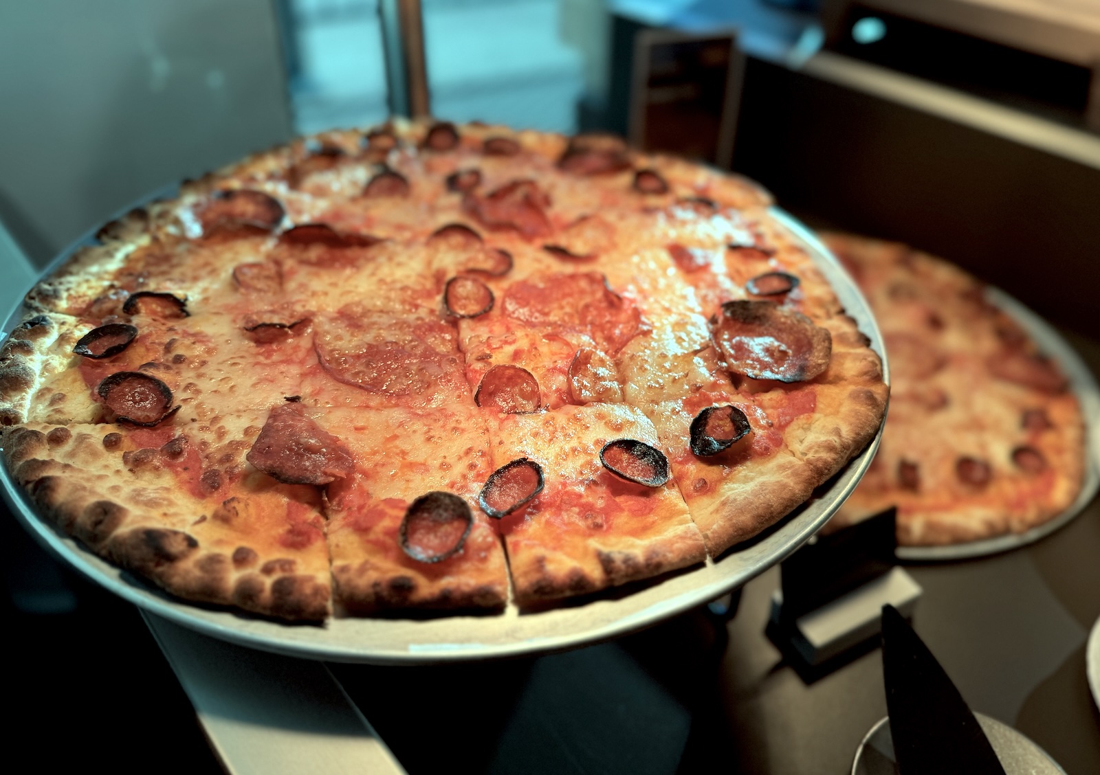 A pepperoni pizza cut into square slices on a metal tray.
