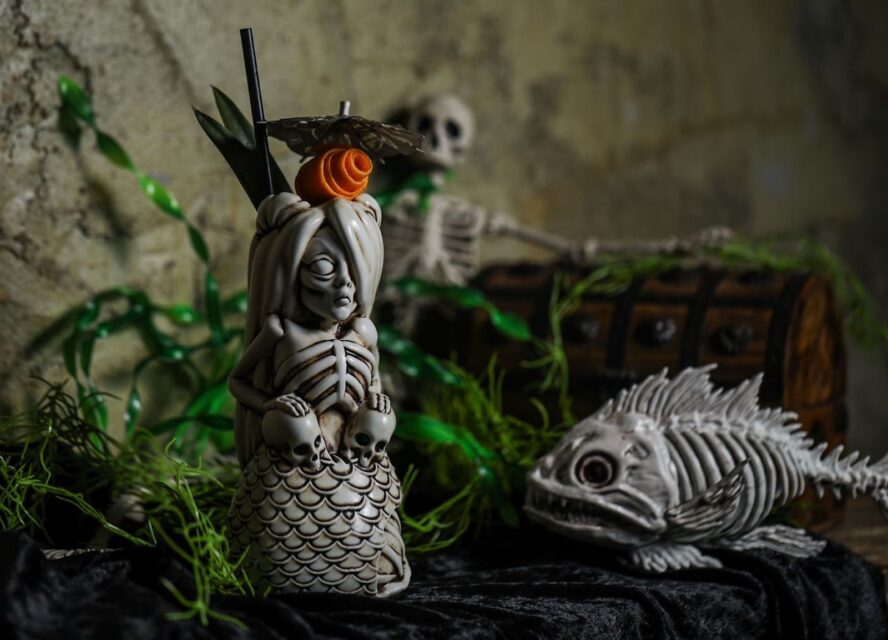 Halloween themed tiki mugs. One is a skeleton mermaid and the other is a fish skeleton.