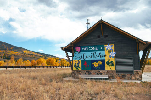 A colorful Welcome to Silverthorne mural in front of golden aspens
