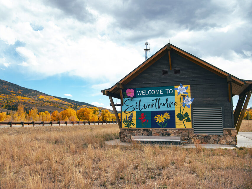 A colorful Welcome to Silverthorne mural in front of golden aspens