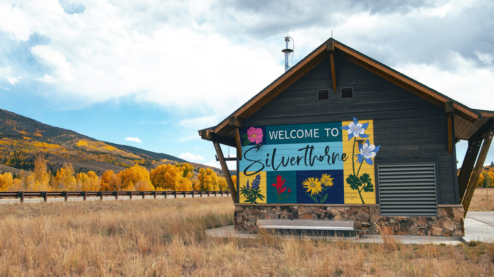 A colorful Welcome to Silverthorne mural in front of golden aspens