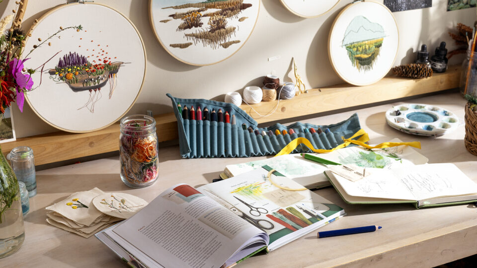 Various art supplies and embroidery supples on a work table
