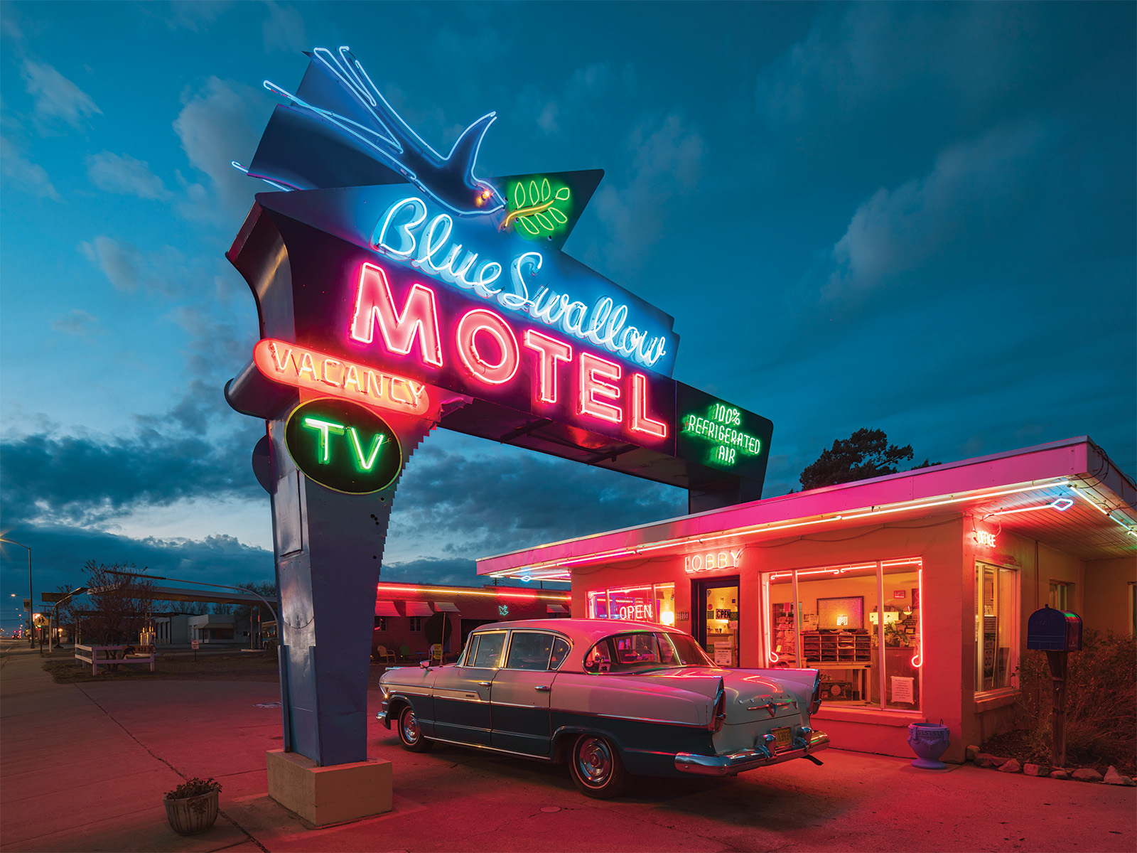 A neon motel sign with an old-school car