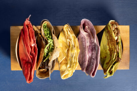 Red, brown, yellow, purple, and green crepes, shot overhead