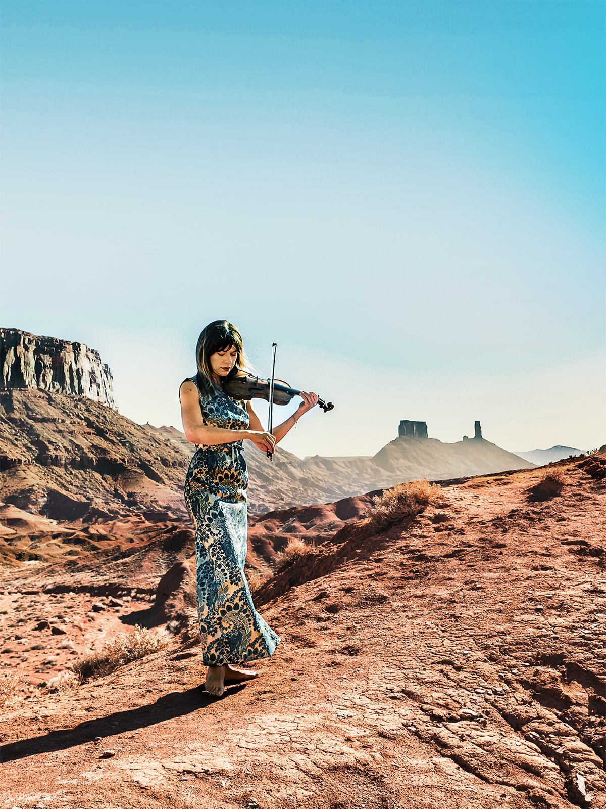 A woman plays a violin in the desert