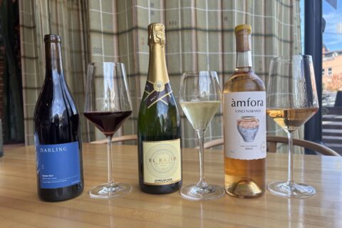 three bottles of wine in a row, each with a glass of wine next to it.