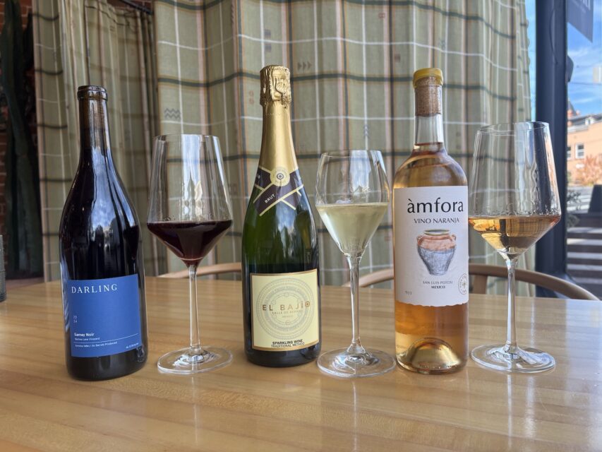 three bottles of wine in a row, each with a glass of wine next to it.