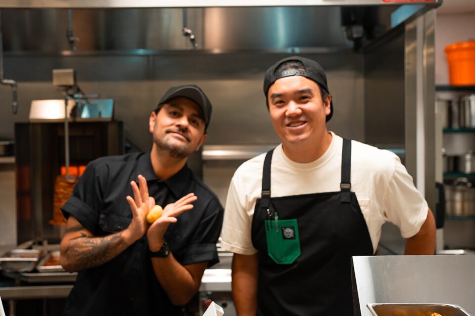 Chef Michael Diaz de Leon in black shirt and hat (left) and Tommy Lee (right) in white t shirt and black hat in front of their restaurant kitchen.