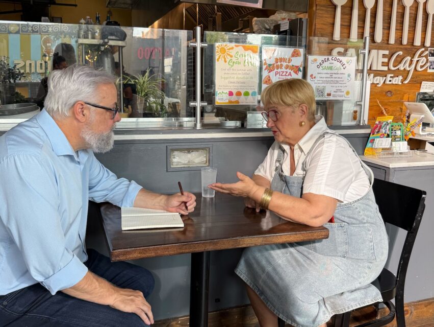 A man (left) sits at a table in SAME Cafe in Denver with chef Lidia Bastianich