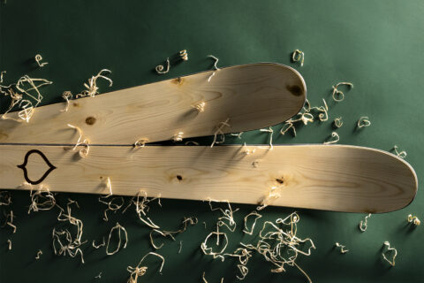 A pair of Wagner Custom Skis Hero’s Spruce Skis on a green background with wood shavings