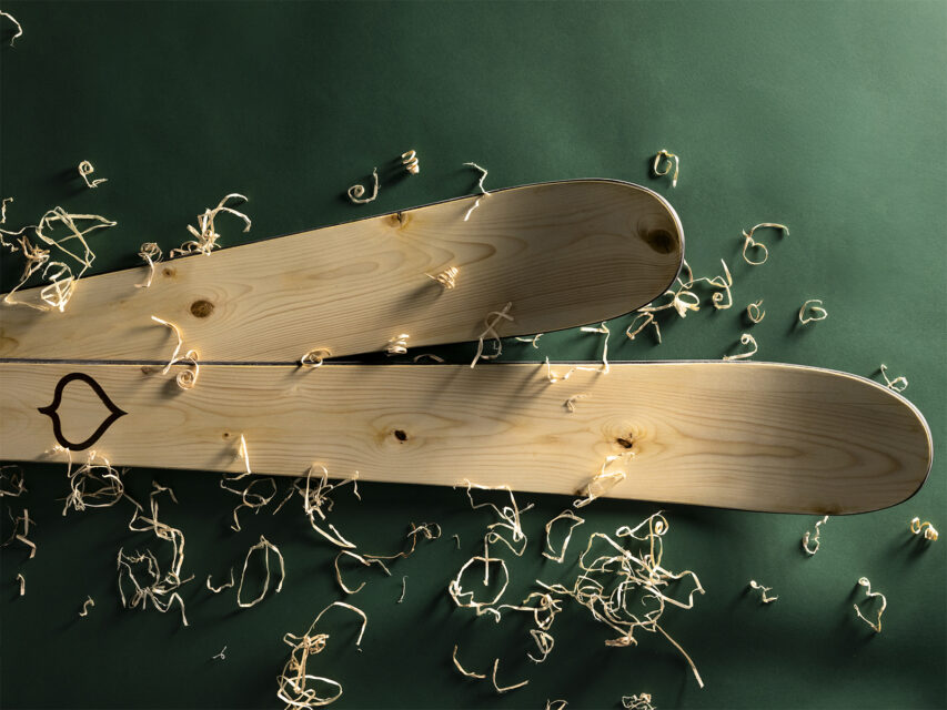 A pair of Wagner Custom Skis Hero’s Spruce Skis on a green background with wood shavings