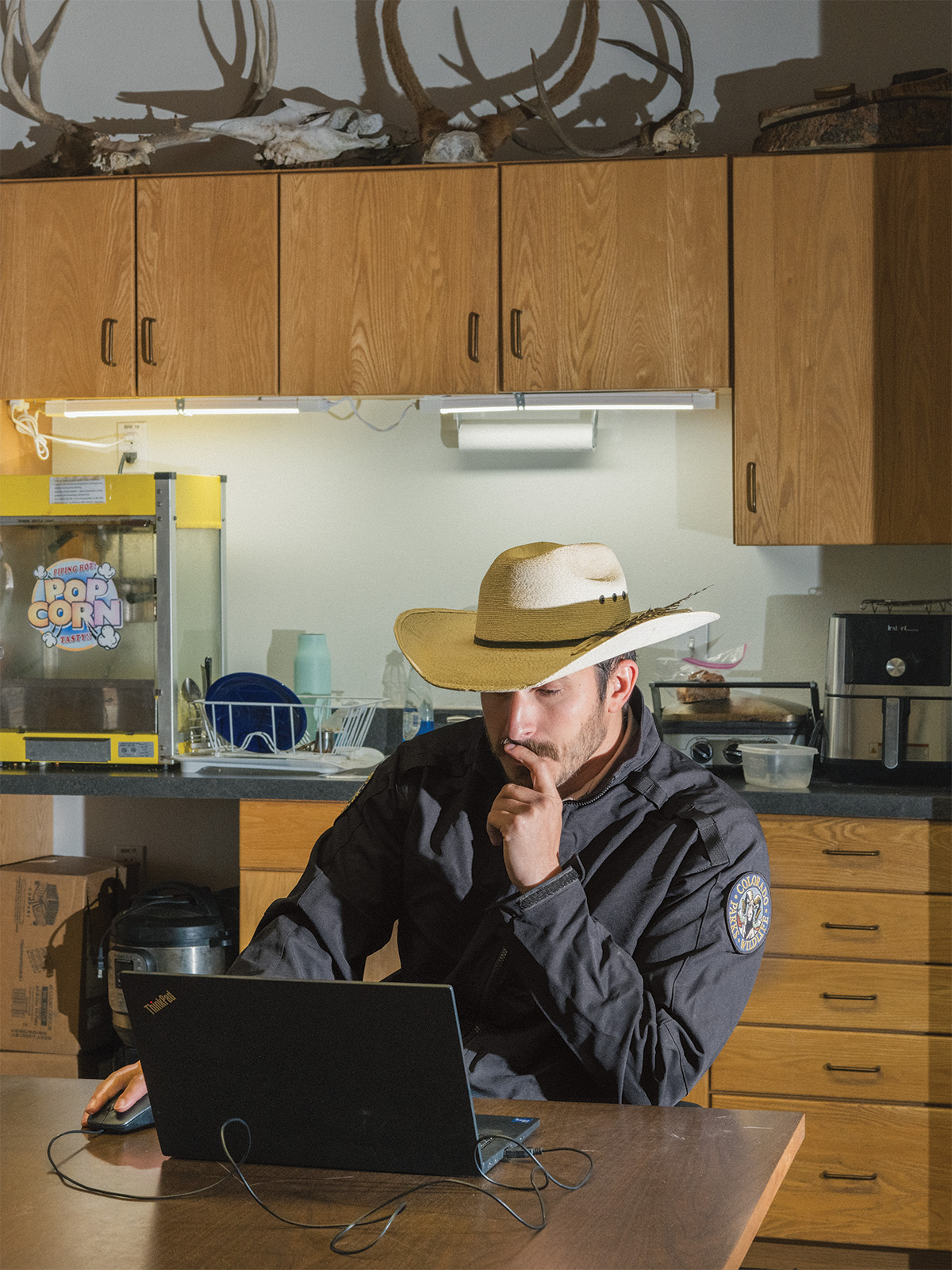 Adam Baca, the wolf conflict coordinator for Colorado Parks and Wildlife, working on a laptop