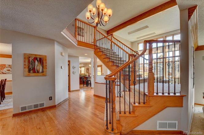 An 80s entryway with orange oak floors and old-school stairs