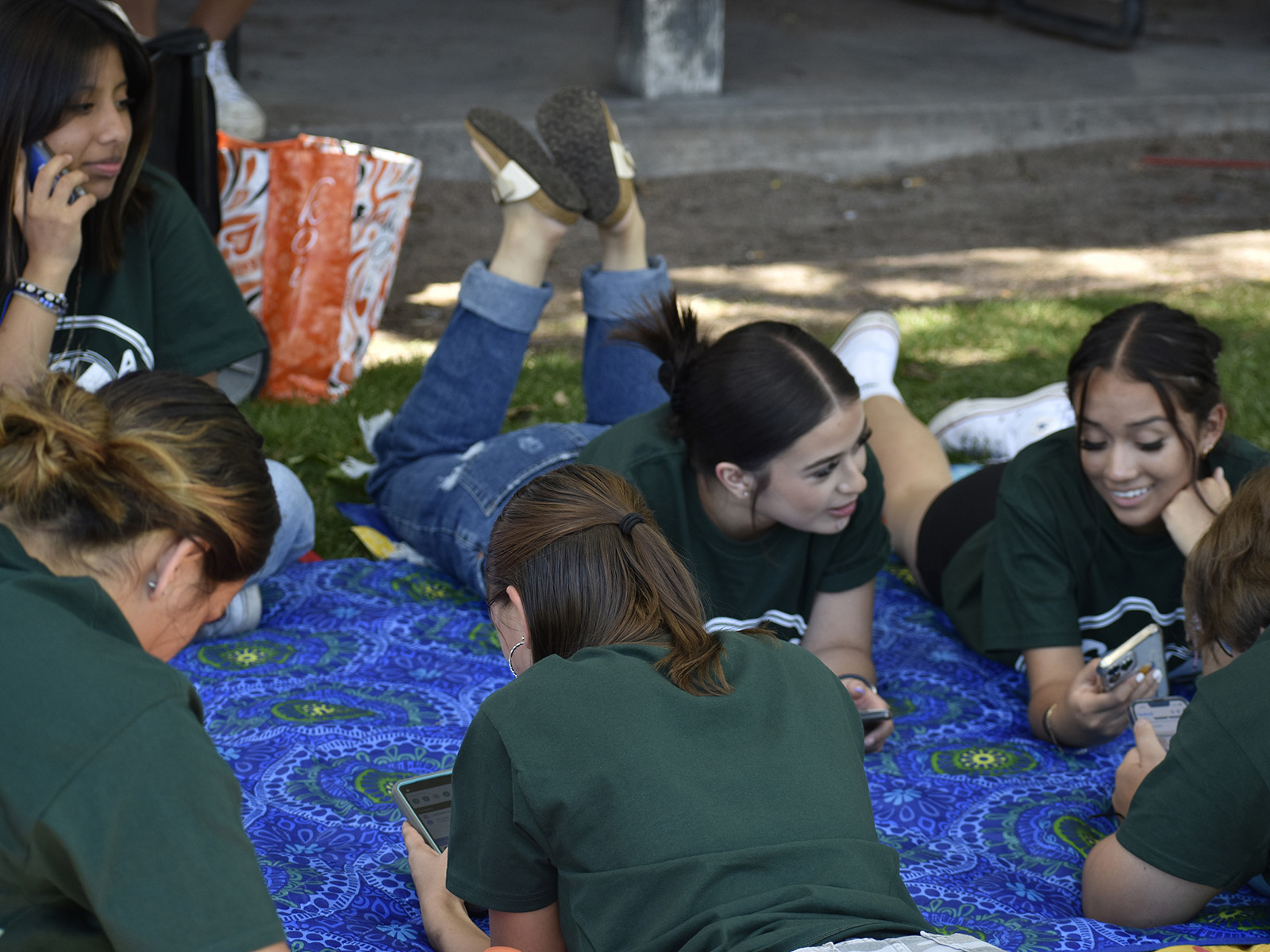 Adams State University students chat on a blanket in the grass